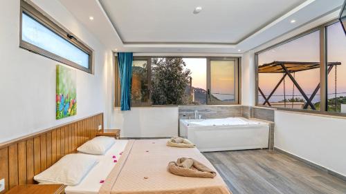 two beds in a room with a tub and windows at Secluded Sea View Honeymoon Escape Jacuzzi Private Pool-Villa Bella1 Orkide in Üzümlü