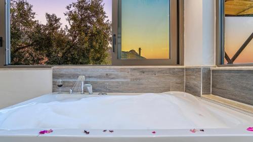 a bath tub in a bathroom with two windows at Secluded Sea View Honeymoon Escape Jacuzzi Private Pool-Villa Bella1 Orkide in Üzümlü