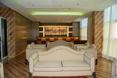 a waiting room with white couches and a bar at Galaxy La Palm Royal Hotel in Port Harcourt