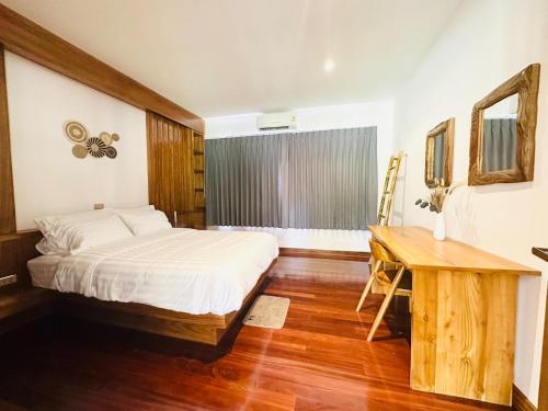 a bedroom with a bed and a desk and a window at Ploythai Villa 2 in Haad Pleayleam