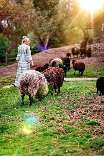 a woman in a dress standing next to a herd of sheep at Chata Na Górce in Ostrowice