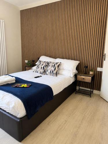 a bedroom with a large bed with a wooden wall at Wellingborough Luxury Staycation 3 Bed 2 Bath in Wellingborough
