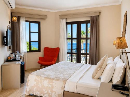 a bedroom with a bed and a red chair at Torbahan Boutique Hotel & Beach Club in Torba