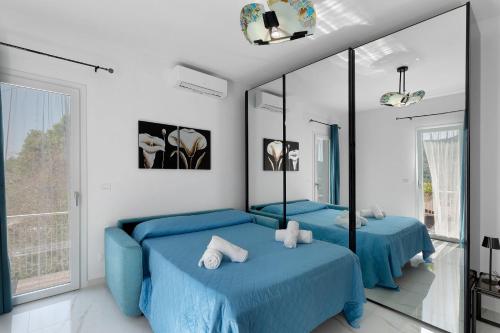 two blue beds in a room with mirrors at Casa Rosetta - vicino Bordighera in Vallebona
