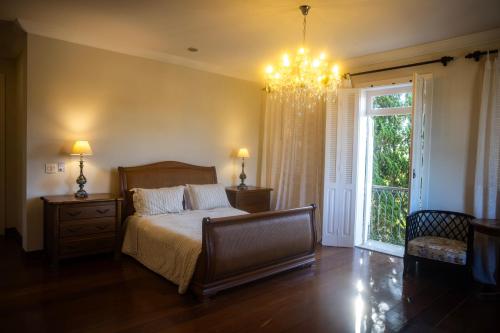 a bedroom with a bed and a chandelier at Hotel Boutique Inconfidentes in Tiradentes