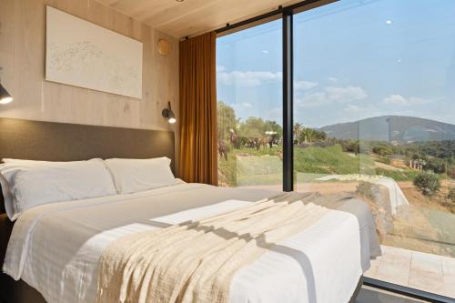 a bedroom with a large bed and a large window at Cork Valley - Mirror Houses in Hontanar