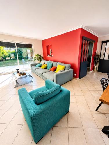 a living room with two couches and a red wall at Le Petit Paradis Lescurien in Lescure-dʼAlbigeois