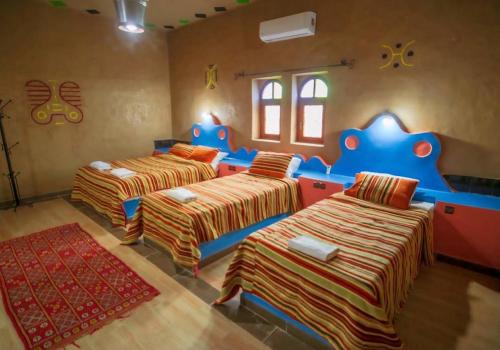a room with three beds in a room at Riad Kasbah Le Touareg in Merzouga