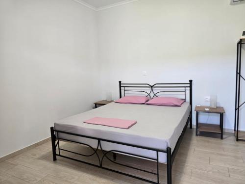 ein Schlafzimmer mit einem Bett mit rosa Kissen in der Unterkunft Garden Room by the Vineyard Salamis in Aiándion