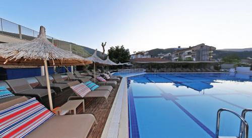 a swimming pool with lounge chairs and umbrellas next to a hotel at Aloria Garden Hotel in Erdek