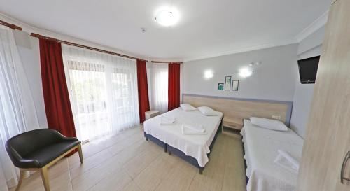 a room with two beds and a chair and a television at Aloria Garden Hotel in Erdek