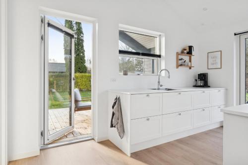 a white kitchen with a sink and a window at Modern Holiday Home With Annex And 10 Beds in Rude