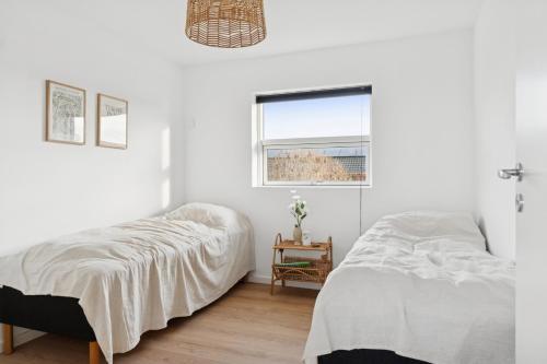 two beds in a white room with a window at Modern Holiday Home With Annex And 10 Beds in Rude