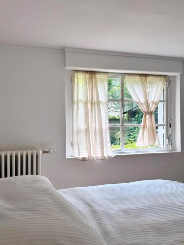 a white bedroom with a bed and a window at Grand T2 neuf Chartrons in Bordeaux