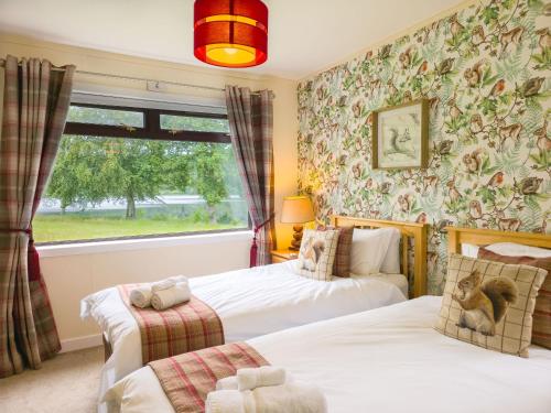 a bedroom with two beds and a window at Kinloch Lodge in Drumnadrochit