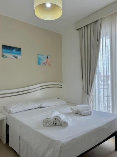 a white bedroom with a bed with towels on it at Hotel Perla Dello Ionio in Torre Lapillo