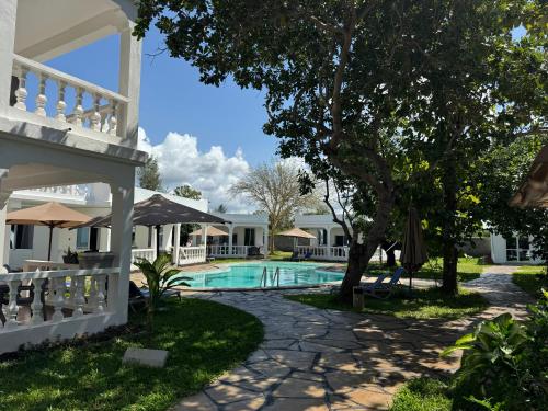 a villa with a swimming pool and a tree at M&H Boutique Hotel in Mombasa