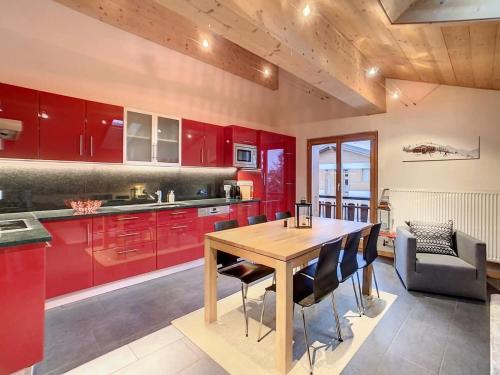 eine Küche mit roten Schränken und einem Holztisch in der Unterkunft Asters 8 in Verbier