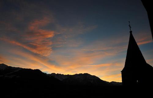 a silhouette of a church with a sunset in the background at Laiterie 1 in Verbier