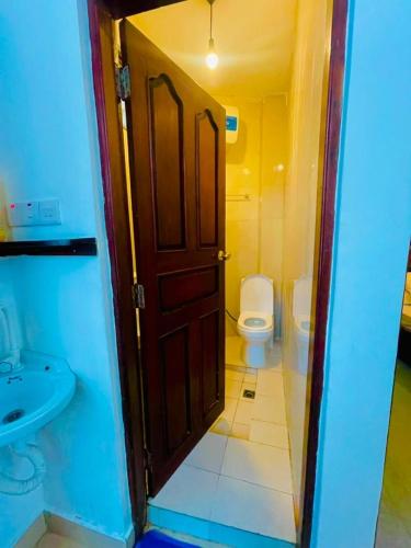 a bathroom with a toilet and a sink and a door at ZANZInest Apartment in Kituoni