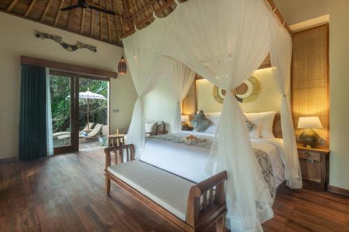a bedroom with a bed with a canopy at The Compass Rose Valley in Ubud