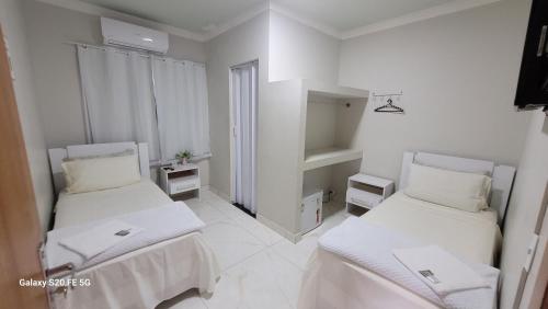 a white room with two beds in it at Hotel Hiperion Maringá in Maringá