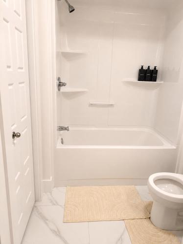 a white bathroom with a tub and a toilet at Modern Riverview Suite Near Downtown Moncton in Riverview
