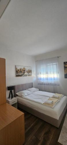 a bedroom with a large white bed and a window at Apartman FIKA in Prijepolje
