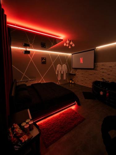a room with a bed and a tv with a red light at Suite O'Dream - Jacuzzi - Cinéma - Climatisation in Fleury-les-Aubrais