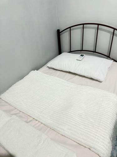 a white bed with a black frame and white sheets at Amori Spaces - MRG in Maribago