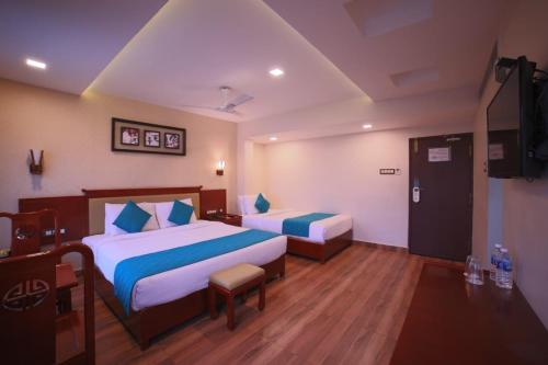 a hotel room with two beds and a television at Hotel President in Madurai