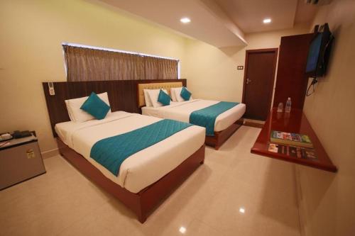 a hotel room with two beds and a flat screen tv at Hotel President in Madurai