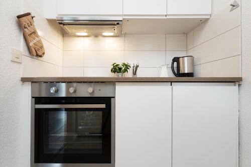 a kitchen with white cabinets and a stove top oven at Waldstraße 2 Ferienwohnung Volkenborn in Kellenhusen