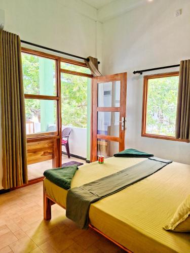 a bedroom with two beds and a large window at Eagle Resort Arugambay in Arugam Bay