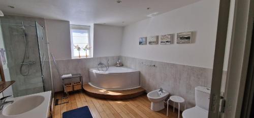 a bathroom with a tub and a sink and a toilet at B&B Villa Des Raisins in Bruges
