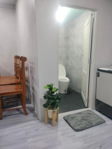 a bathroom with a toilet and a table and a chair at บ้านสวนริมทาง in Ban Pha Saeng Lang