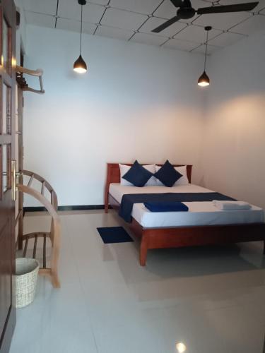 a bedroom with a bed with blue pillows on it at MAYU Homestay in Dickwella