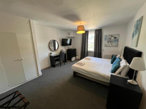 ein Schlafzimmer mit einem Bett, einem Schreibtisch und einem Spiegel in der Unterkunft Antrobus Arms Hotel in Amesbury
