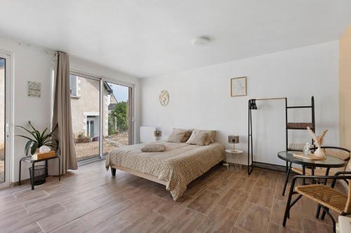 a white bedroom with a bed and a table at La Parenthèse du Loir in Château-du-Loir