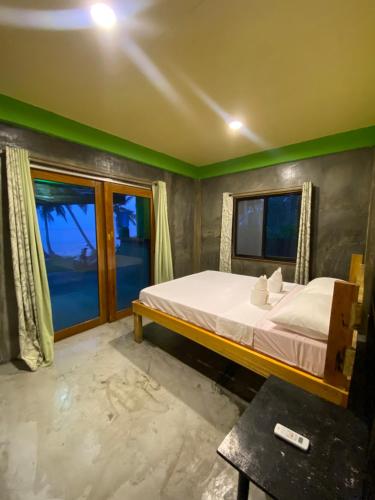 a bedroom with a bed and a large window at Kapunoan Beach House in Burgos
