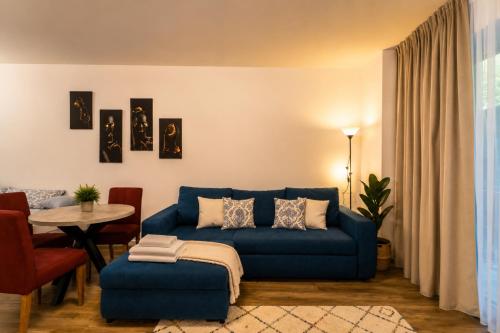 ein Wohnzimmer mit einem blauen Sofa und einem Tisch in der Unterkunft Wise Nest Studio with pool and spa in Sinaia