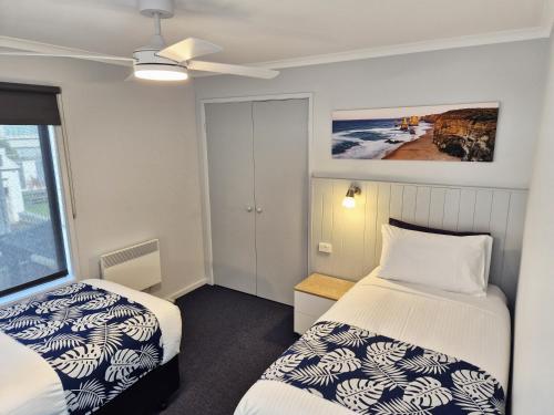 a small room with two beds and a window at Apollo Bay Waterfront Motor Inn in Apollo Bay