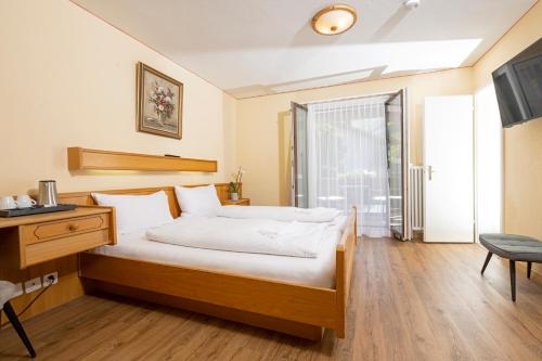 ein Schlafzimmer mit Bett, Schreibtisch und Fenster in der Unterkunft Hotel Galina Self-Check-in in Malbun