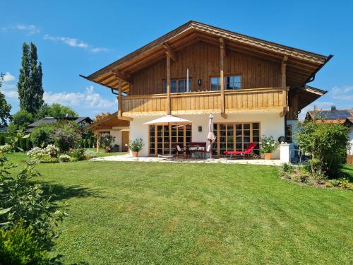 a house with a wooden roof and a yard at CHIEMSEE MOUNTAIN LODGE - adults only - Eleganz auf 95qm - Traumblick - XL-Balkon - Privatsphäre in Bernau am Chiemsee