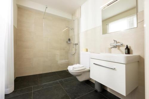 ein Badezimmer mit Toilette, Waschbecken und Dusche in der Unterkunft Hotel Galina Self-Check-in in Malbun