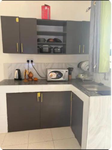 a kitchen counter with a sink and a microwave at NewNest in Bungoma