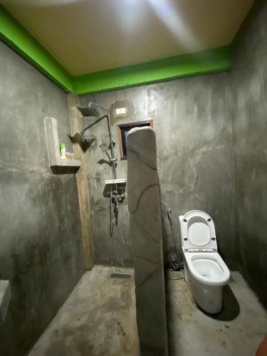 a small bathroom with a toilet and green lighting at Kapunoan Beach House in Burgos