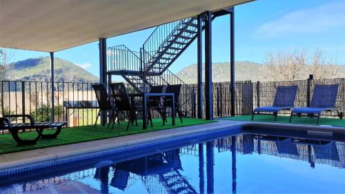 a house with a swimming pool with chairs and a staircase at Casa de dos habitaciones con piscina en Cabañeros in Navas de Estena