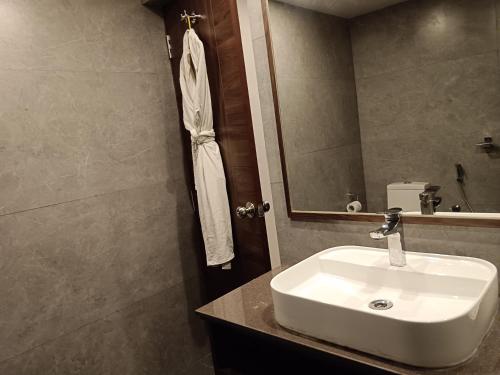 a bathroom with a white sink and a mirror at The Presidency in Bhubaneshwar