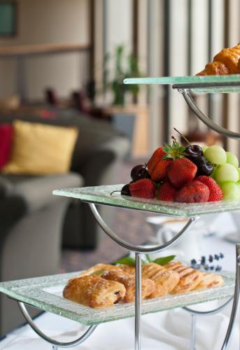 eine dreistöckige Etagere mit Speisen, Obst und Gebäck in der Unterkunft Copthorne Hotel & Resort Lakefront Queenstown in Queenstown